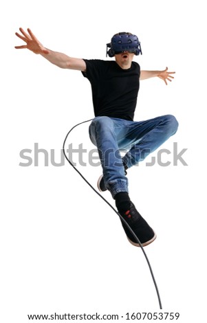 Young man imagines himself a superhero while using VR glasses for playing computer game. Male portrait on white background. 