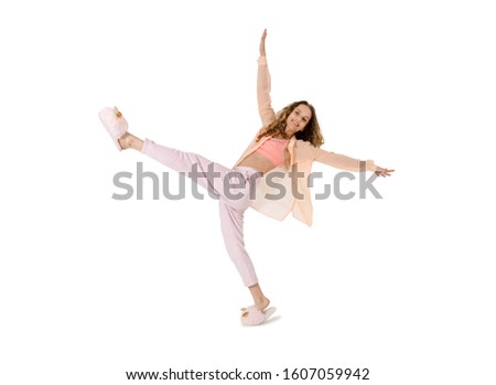 Young woman in pajamas and slippers having fun dancing  on a white background

