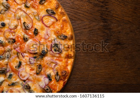 Tasty looking Pizza,Pica with pepperoni, cheese, sauce, tomatoes, garlic, fish, and mushrooms on a yellow background with greens, gluten free, with meat. with space. on a wood surface.