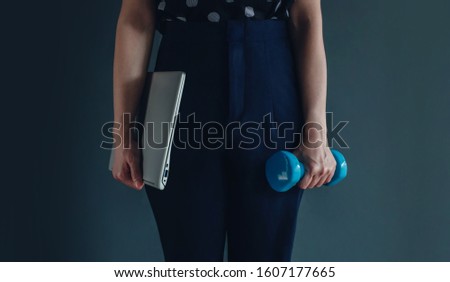 Work Life Balance Concept, present by Business Working Woman holding a Laptop by right hand and another hand with a Dumbbell, Lifestyle of Modern People. Croped image with Copy Space 