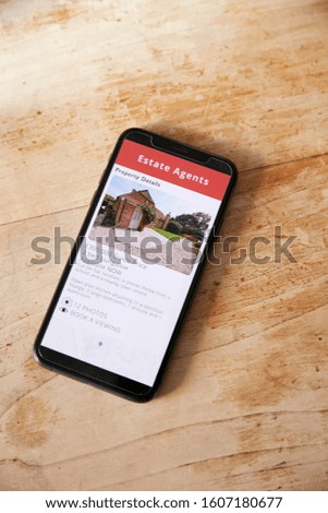 Close Up Of Mobile Phone With Realtors Property App Lying On Table