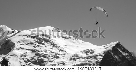 Paraglider and beautiful Mont Blanc mountain at background. Haute Savoie, France. Adventure, eco planet, climat change, environment, ecology concepts. Old historic retro black white photo banner.
