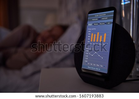Woman Sleeping In Bed With Sleep Data App Running On Mobile Phone On Bedside Royalty-Free Stock Photo #1607193883