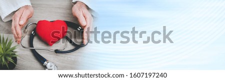 Hands of doctor protecting a red heart; panoramic banner