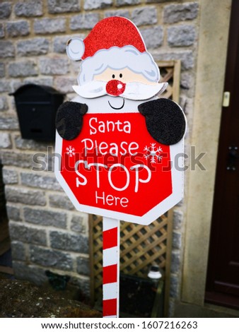 A sign outside a house at Christmas which says Santa Stop Here