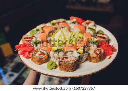 Sushi and rolls in plate on a black background.