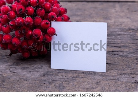 Christmas composition. Paper blank with Rowan hawthorn branch with berries on a wooden background.