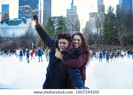 Portrait of a happy young couple smiling, hugging and having fun while ice skating outside in Central Park, NYC