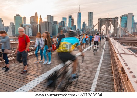 Tourists in New York on Brooklyn bridge with Manhattan skyscrapers on background - Long exposure view on the bridge with blurred people and downtown Manhattan skyline - Travel and architecture