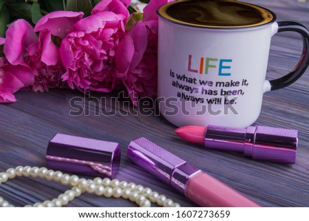Peonies flowers, lipstic and cup of coffee. Close-up. Quote about life.