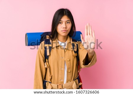 Young chinese traveler woman isolated standing with outstretched hand showing stop sign, preventing you.