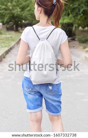 Woman with drawstring bag on the shoulder. Cropped. Royalty-Free Stock Photo #1607332738