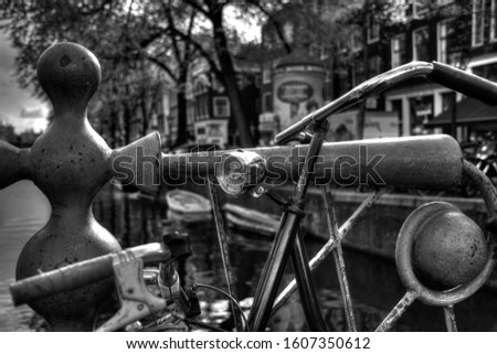 Old bicycle with chrome light. Leaning against a railing over the Amsterdam Canal. In black and white photography.