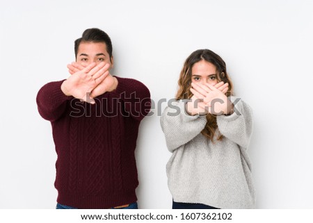 Young couple posing in a white background doing a denial gesture