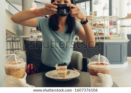 Asian woman is taking a photo of her blueberry cheesecake.