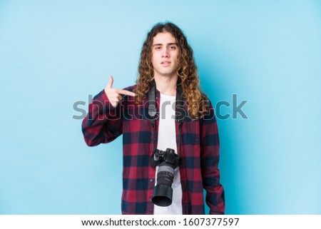 Young caucasian photographer man isolated person pointing by hand to a shirt copy space, proud and confident