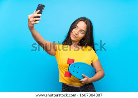 Young skater woman over isolated blue background