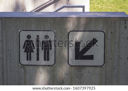 Close up of sign for the toilet with a down pointing arrow