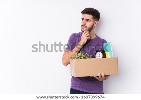 Young caucasian man moving a new home isolated relaxed thinking about something looking at a copy space.