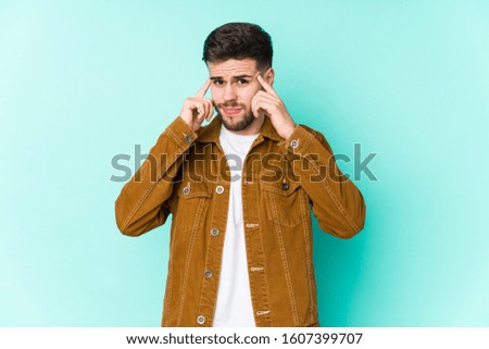 Young handsome man focused on a task, keeping forefingers pointing head.