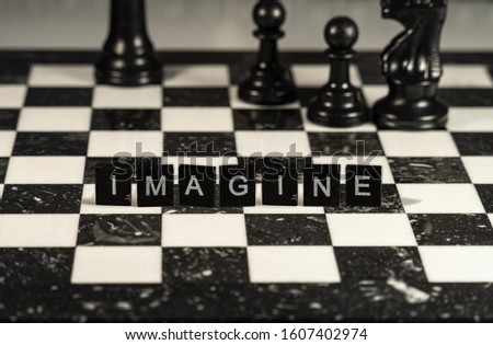 The concept of Imagine represented by black letter tiles with chessboard background