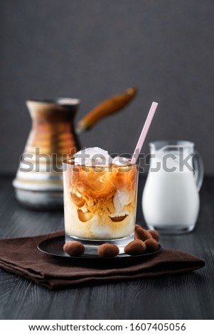 Iced coffee with cream on dark wooden table