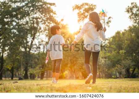 Family and Vacation Time concept.Happy Young Family Mother and son walked to hold hands looks happy in the park in the afternoon autumn sunlight,bokeh,Sunny Day Sunset,happily holiday with copy space.