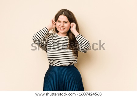 Young curvy woman covering ears with hands.
