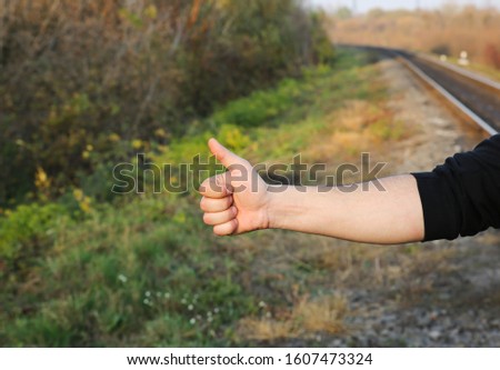 Man is waiting for train on railway tracks outdoors. Travel concept. Summer ideas. Late transport. Holding thumb up with like sign.