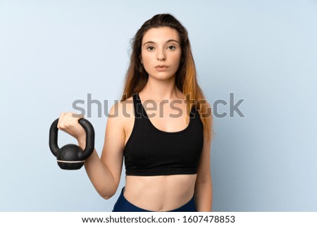 Young brunette girl making weightlifting with kettlebell over isolated background