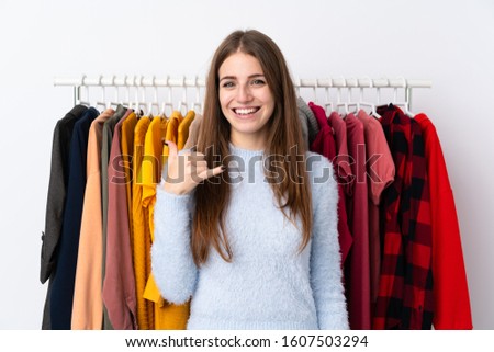 Young woman in a clothing store making phone gesture