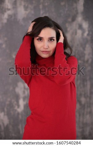 portrait of a beautiful girl with dark hair in a red turtleneck in a good positive mood