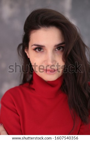 portrait of a beautiful girl with dark hair in a red turtleneck in a good positive mood
