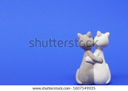 Two cats are hugging. Cats are close and love each other. Valentines Day. Figurine cats in love. Cats together are a symbol of lovers. Congratulation. Place for text. Blue color.
