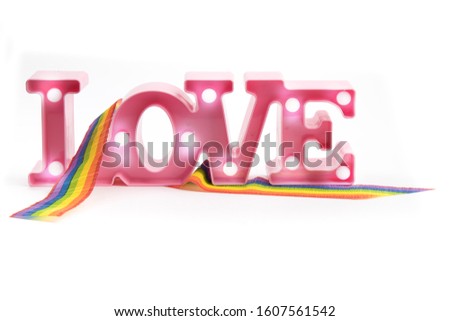 pink illuminated Valentines LOVE letter sign with a rainbow ribbon isolated on white
