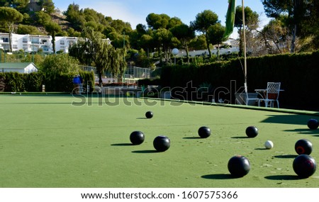 Lawn bowls balls positioned on a smooth playing surface, a bowls green. 