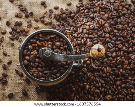 High top view of coffee grinder with roasted coffee beans on table