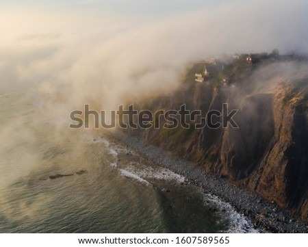 Dana Point cliff side peaking through the foggy marine layer coming in to the harbor in Orange County