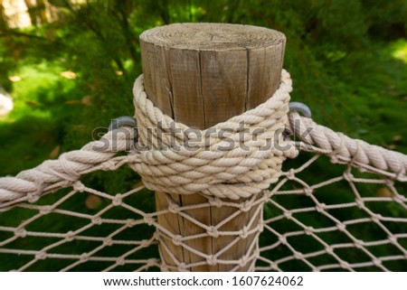 Part of the wooden fence with cord plaiting. Cross pattern on the green background. Cord knots.  
