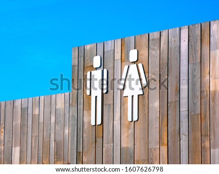 Public restroom toilet signs for with man and woman figures against wooden structure