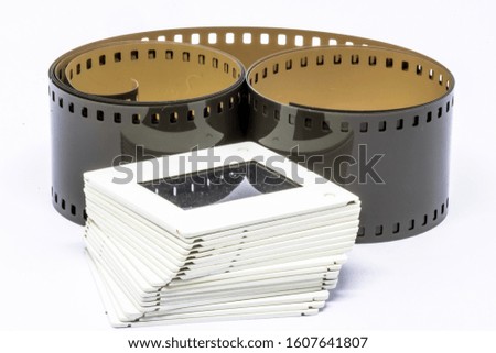 Rolled undeveloped film strip and film slide 35mm stack isolated on white background