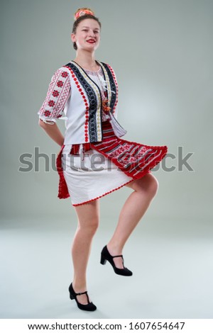 Young Romanian woman in popular costume, dancing on traditional music