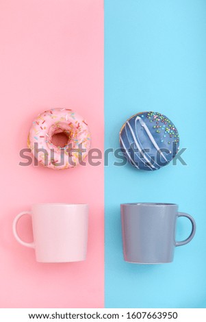 Donuts with icing and coffe cups on pastel blue and rose background. Sweet donuts.