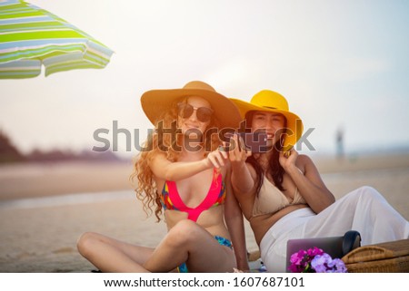 Women are taking photos and Selfie with friends on the sand beach in the summer.
