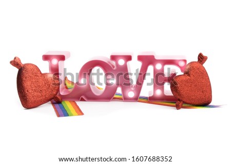 a pink illuminated letter LOVE sign with a rainbow ribbon and glitter cupid hearts isolated on white