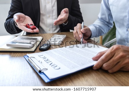 Car rental and Insurance concept, Young salesman giving car's key to customer after sign agreement contract with approved for rent or purchase.