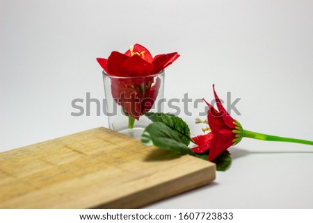 Transparent glass with red flowers on it. Valentine's Day picture concept with white background.