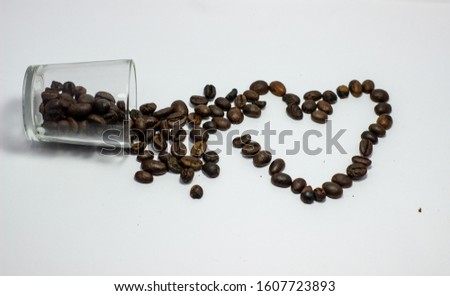 Black coffee spills in a glass form the perfect LOVE. Valentine's Day picture concept with white background.