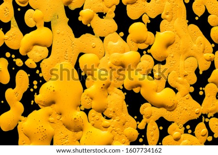 texture of drops of yellow water paint on black