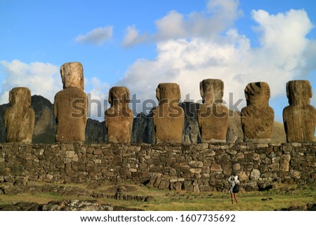 Female traveler photographing the back of gigantic Moai statues at Ahu Tongariki ceremonial platform, Archaeological site on Easter Island, Chile